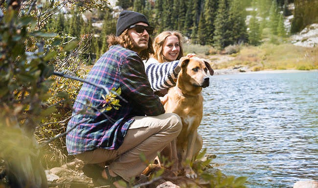 Stunning Surroundings Lifestyle photo of a couple and their dog sit along the river bank